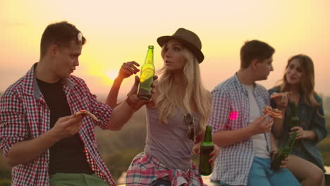 A-loving-couple-on-the-roof-drinks-beer-and-enjoying-the-sunset.-The-girl-in-the-hat-gently-strokes-the-head-of-her-young-man.